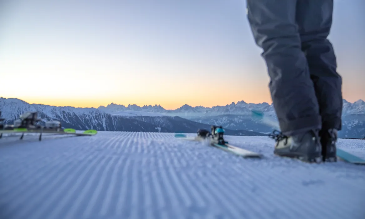 Freshly groomed slope at dawn with Dolomites silhouette, first-line skiing at Klausberg