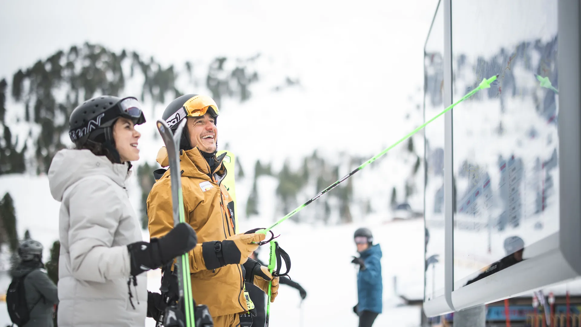 Zwei lachende Skifahrer studieren die Panoramatafel mit Pistenplan der Skiworld Ahrntal