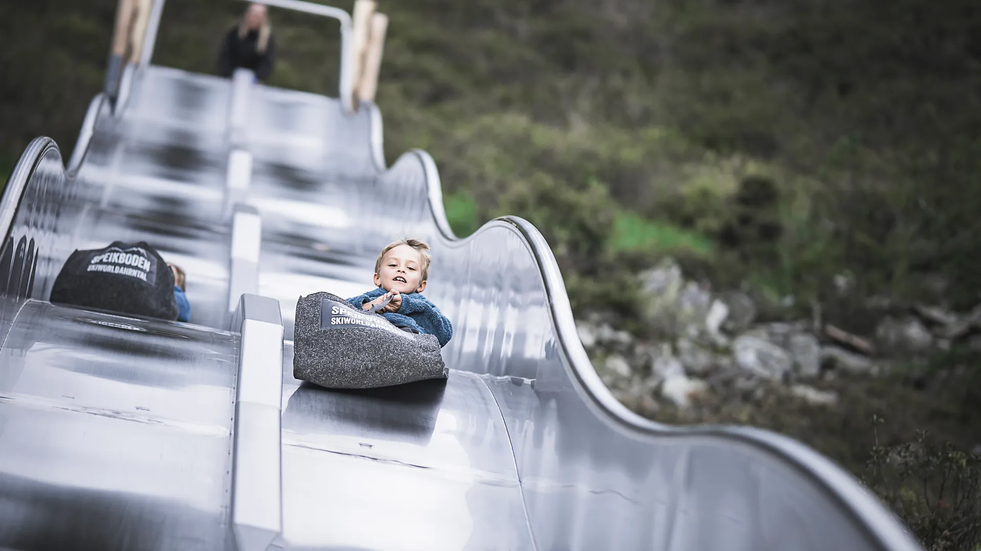 Kind rutscht lachend die Wellenrutsche am Speikboden Familienpark im Ahrntal hinunter