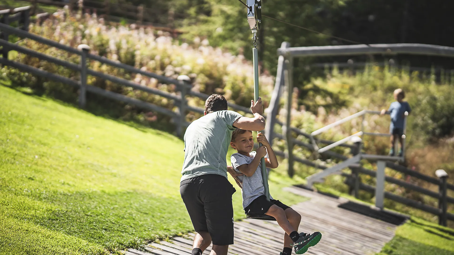Child on zip line at Klausberg mountain playground, father helps push
