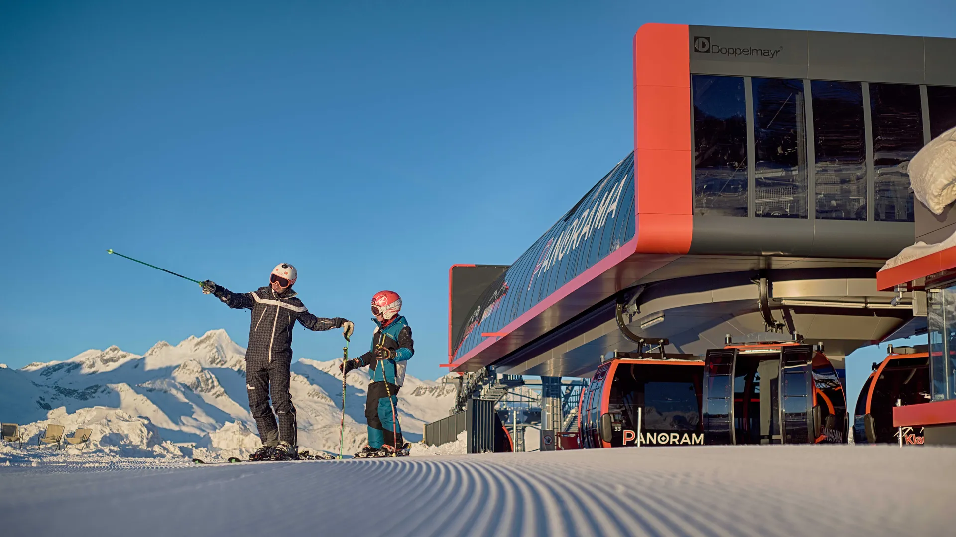 Skilehrer mit Kind auf präparierter Piste vor der modernen Gondelbahn am Klausberg im Ahrntal