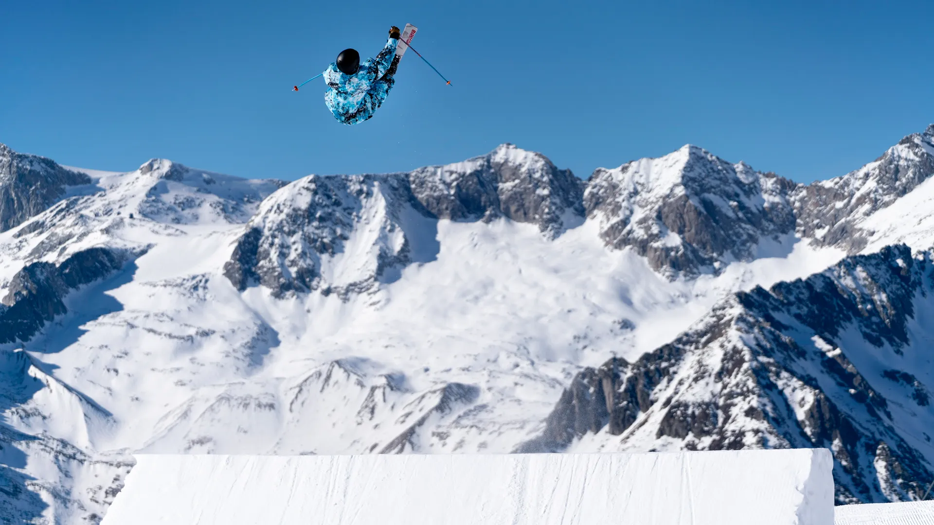 Freestyle skier high in the air with grab trick above the snowpark kicker at Klausberg