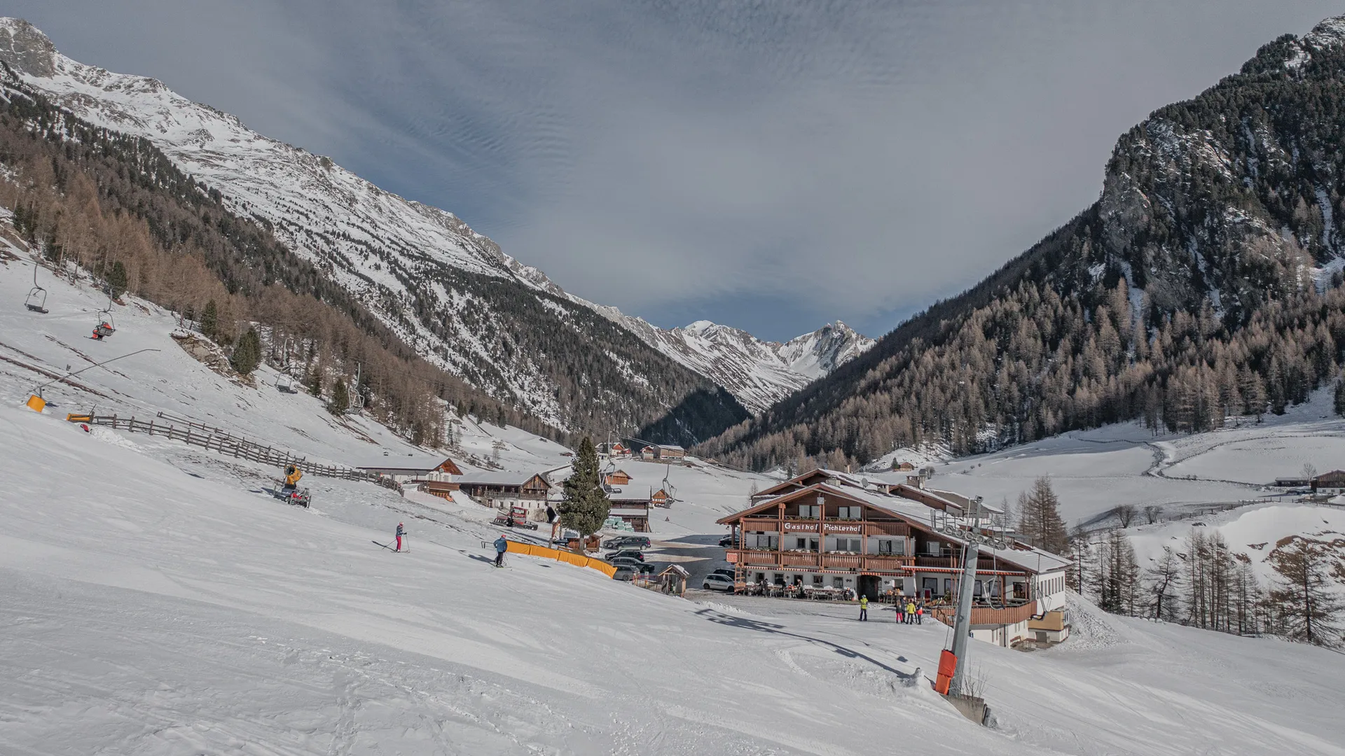 Valley run at Klausberg with view of Pichlerhof guesthouse, chairlift and skiers on groomed slope