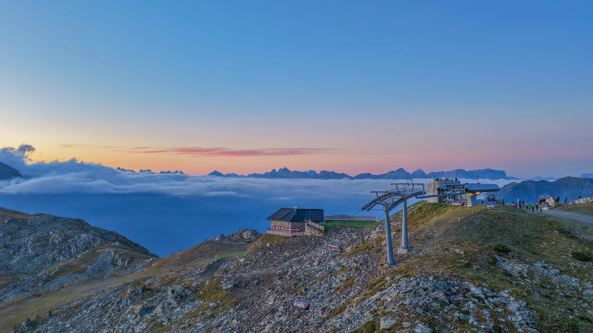 Bergstation mit Sessellift am Klausberg bei Sonnenuntergang über dem Wolkenmeer und Dolomitenpanorama