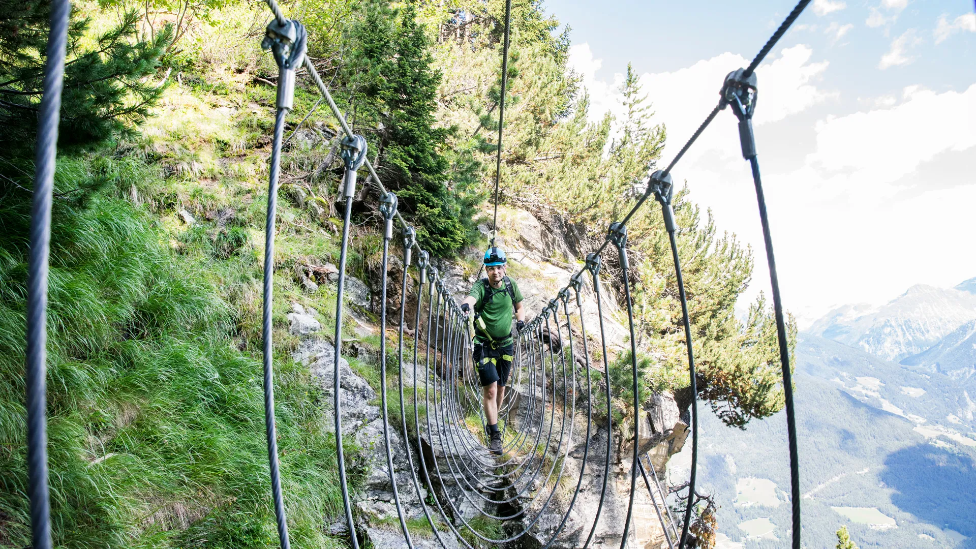 Kletterer überquert Hängebrücke am Klettersteig Speikboden im Sommer