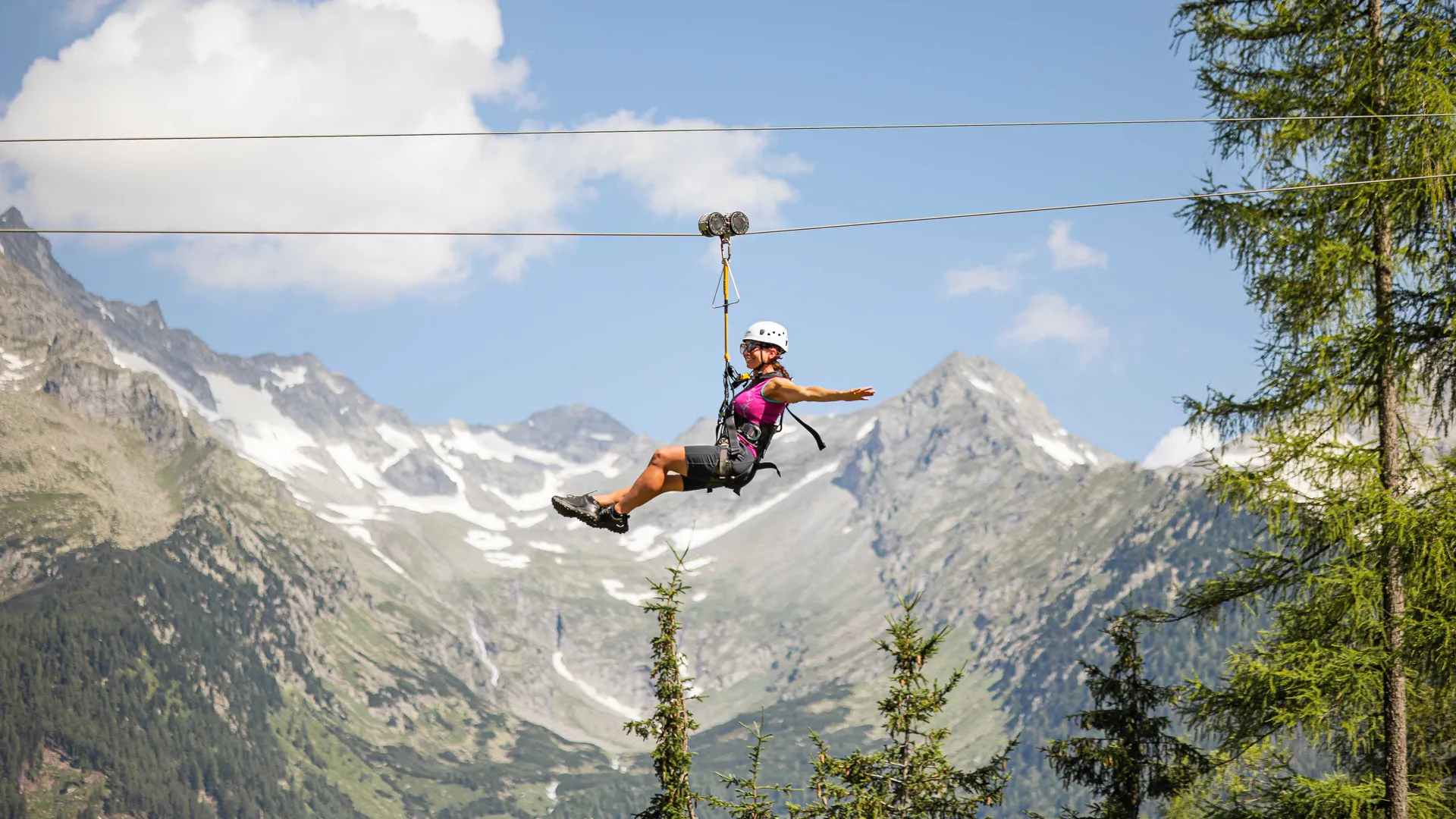 Frau im Freiflug am Skyglider Klausberg über Lärchenwäldern mit Bergpanorama Ahrntal