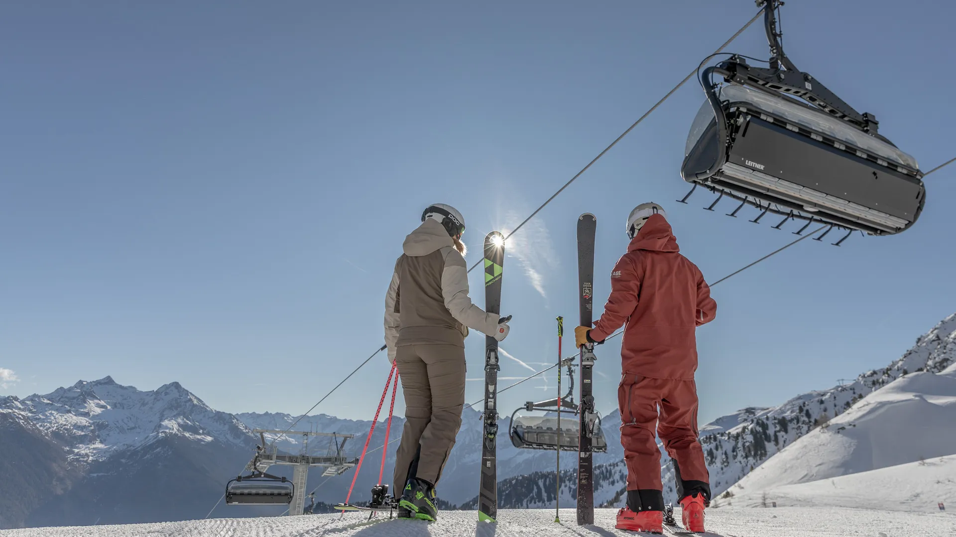 Two skiers at the top station of the chairlift at Speikboden with views of the South Tyrolean Alps