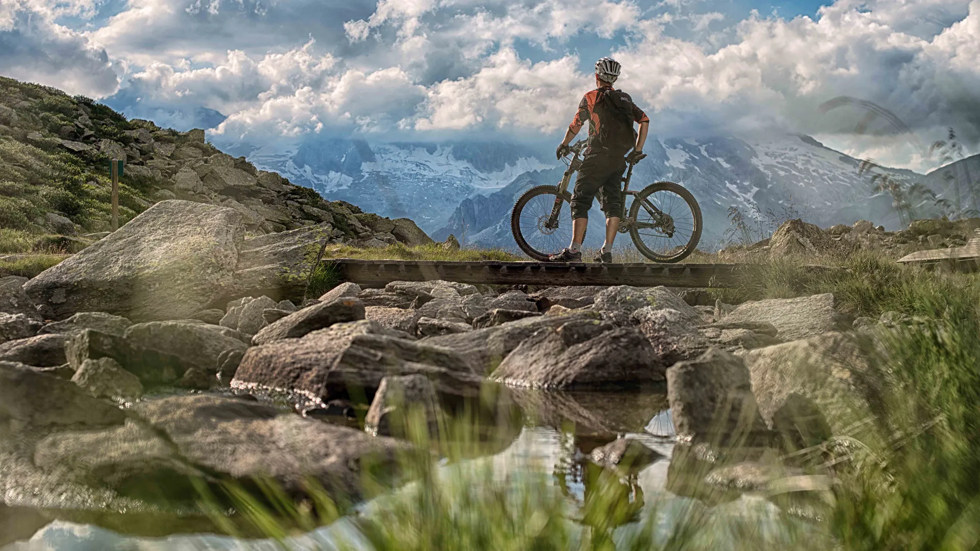 Mountainbiker auf Holzbrücke am Klausberg mit Panorama der Zillertaler Alpen im Sommer