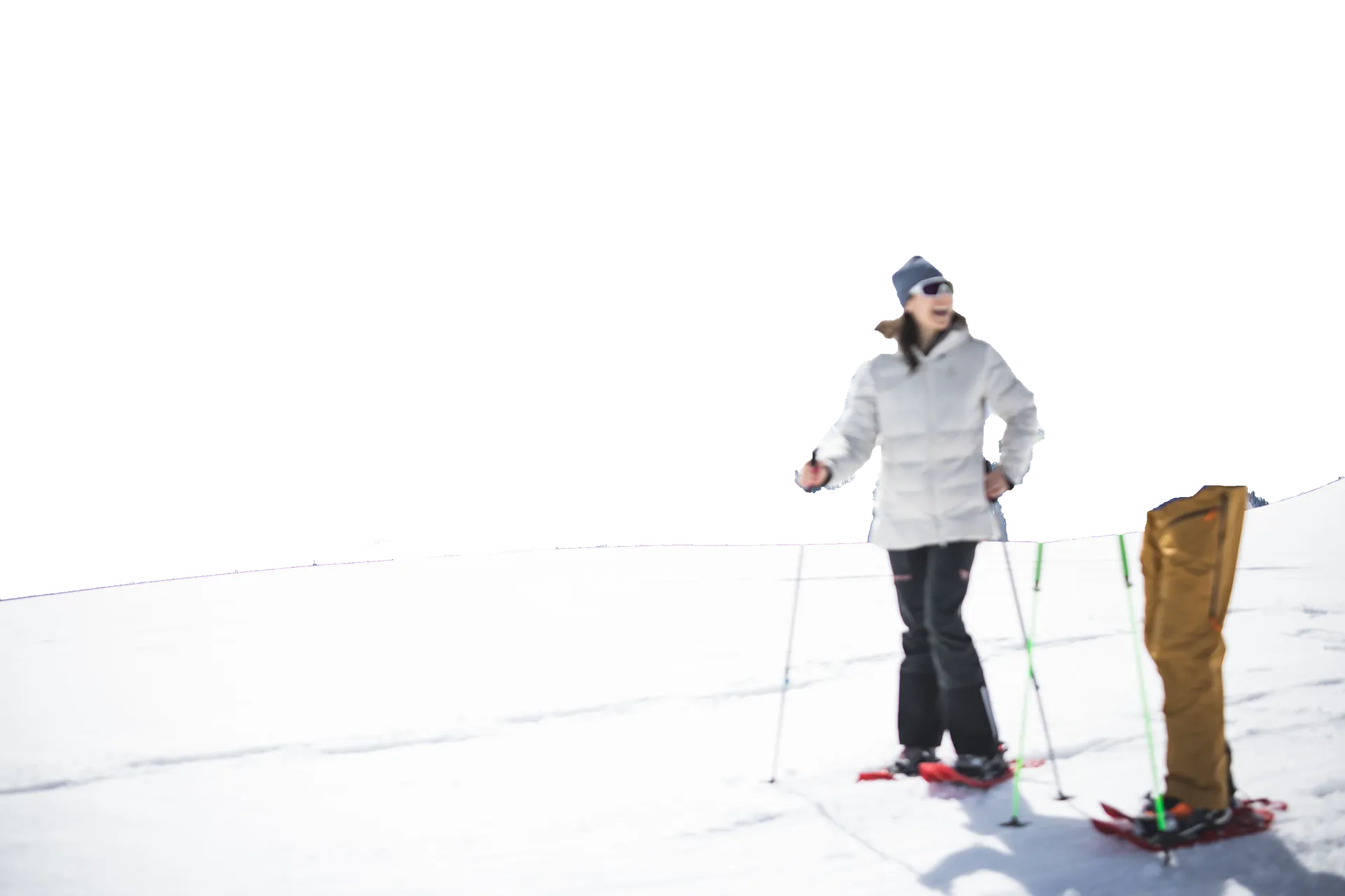Lachende Schneeschuhwanderin in weißer Winterjacke auf sonniger Schneefläche im Ahrntal