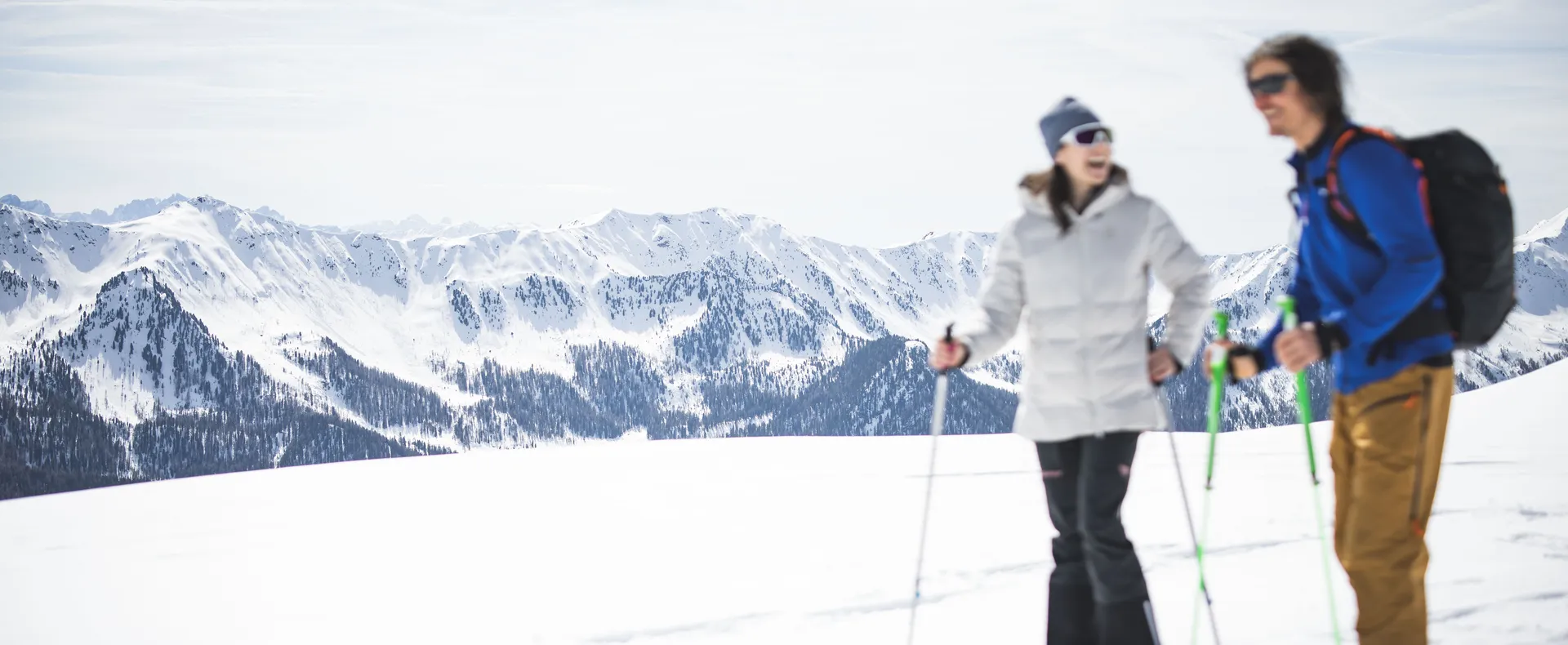 Paar beim Schneeschuhwandern auf sonniger Hochebene im Ahrntal mit Bergpanorama Südtirols