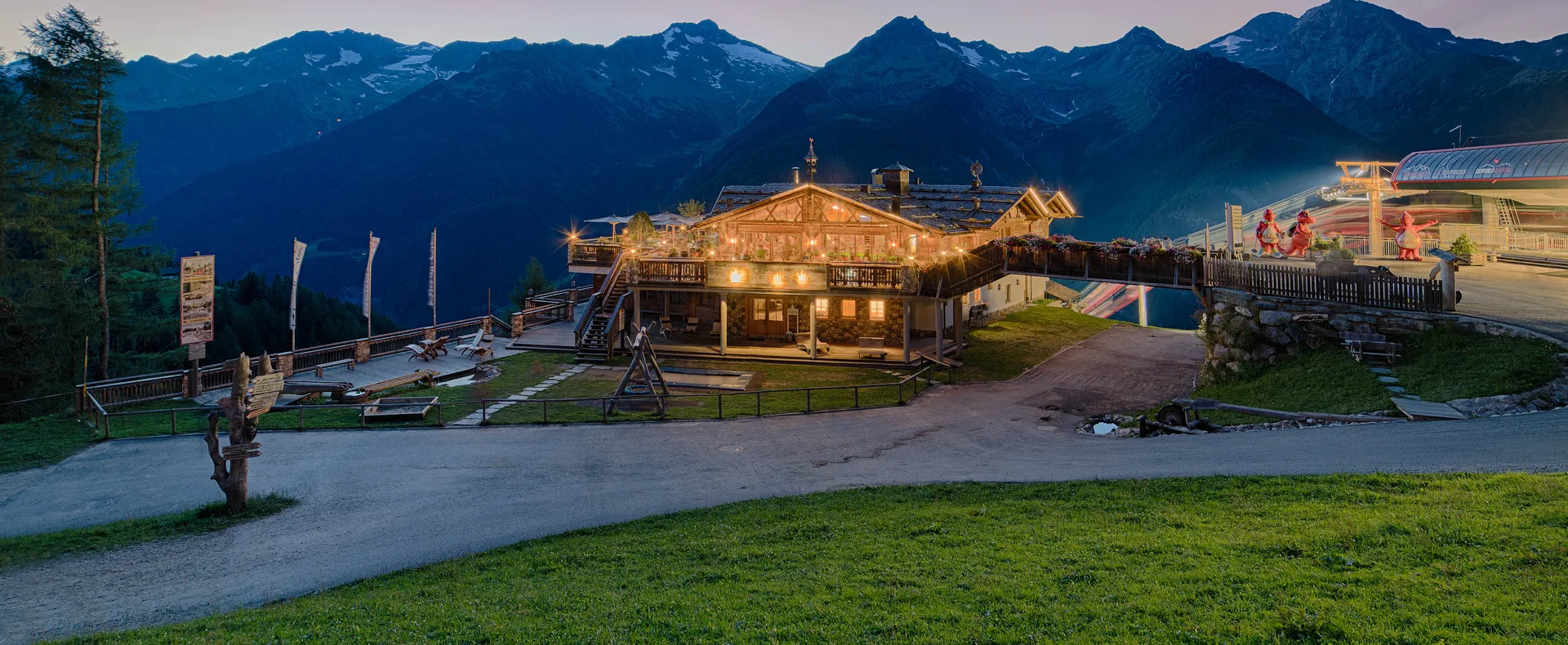 Beleuchtete Almhütte bei Sonnenuntergang mit Panoramablick auf die Zillertaler Alpen am Klausberg