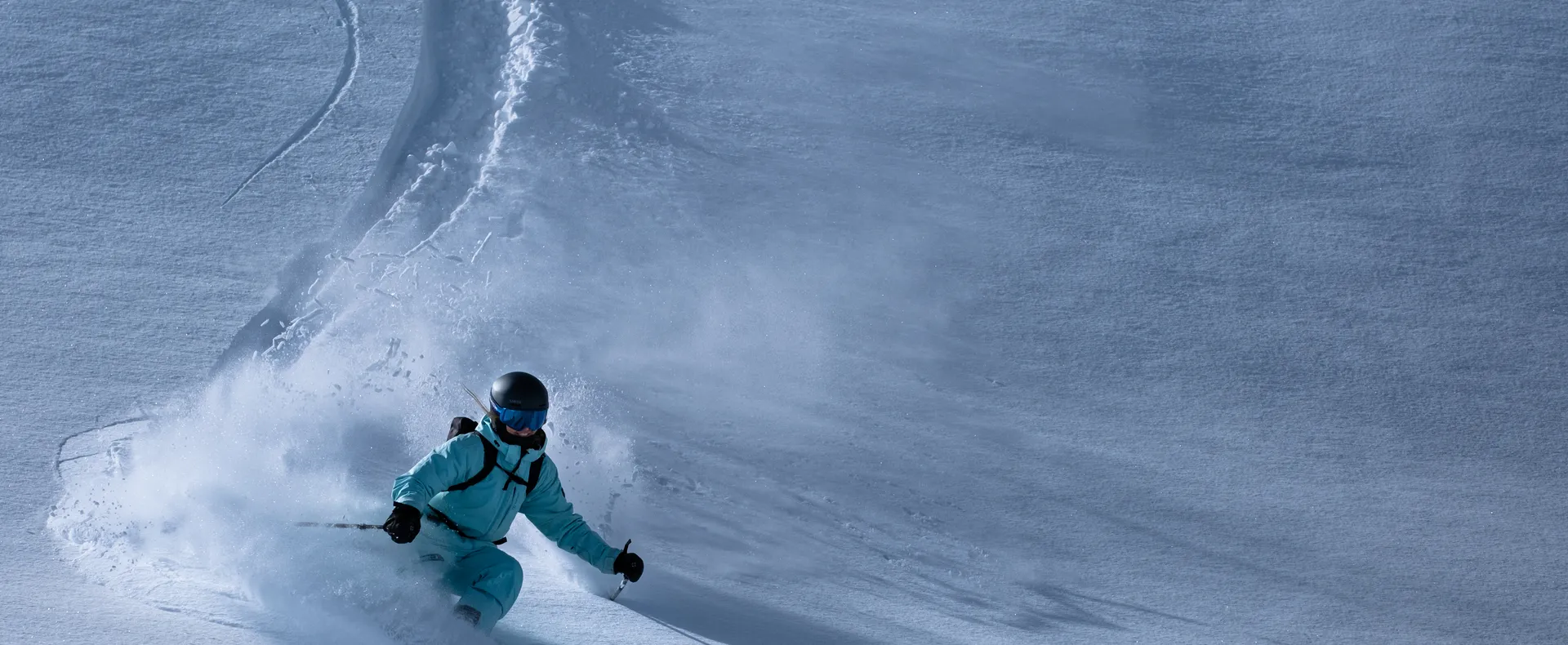 Freeride skier carving through deep powder snow at Klausberg on a sunny winter day