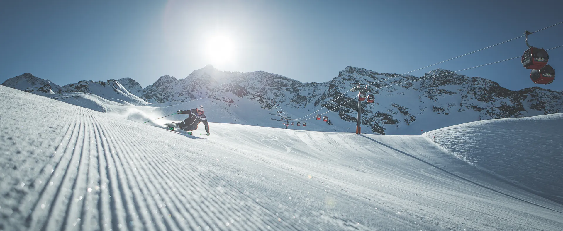 Skier carving on Klausberg slope next to gondola lift on a sunny winter day