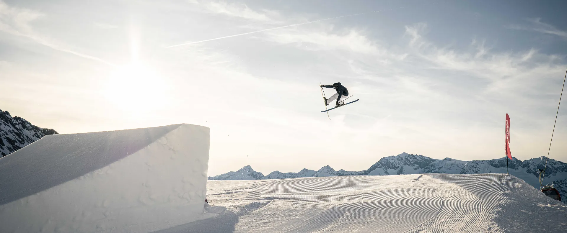 Freestyle skier performing a grab trick in Klausberg Snowpark in golden evening light