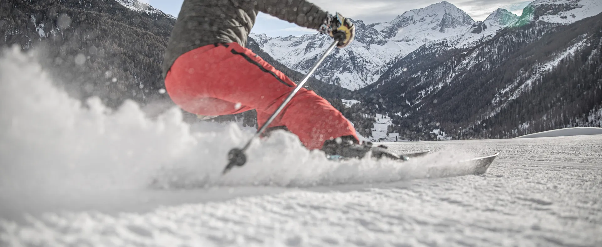 Skier making dynamic carving turn with spraying snow on a slope in Ahrntal South Tyrol