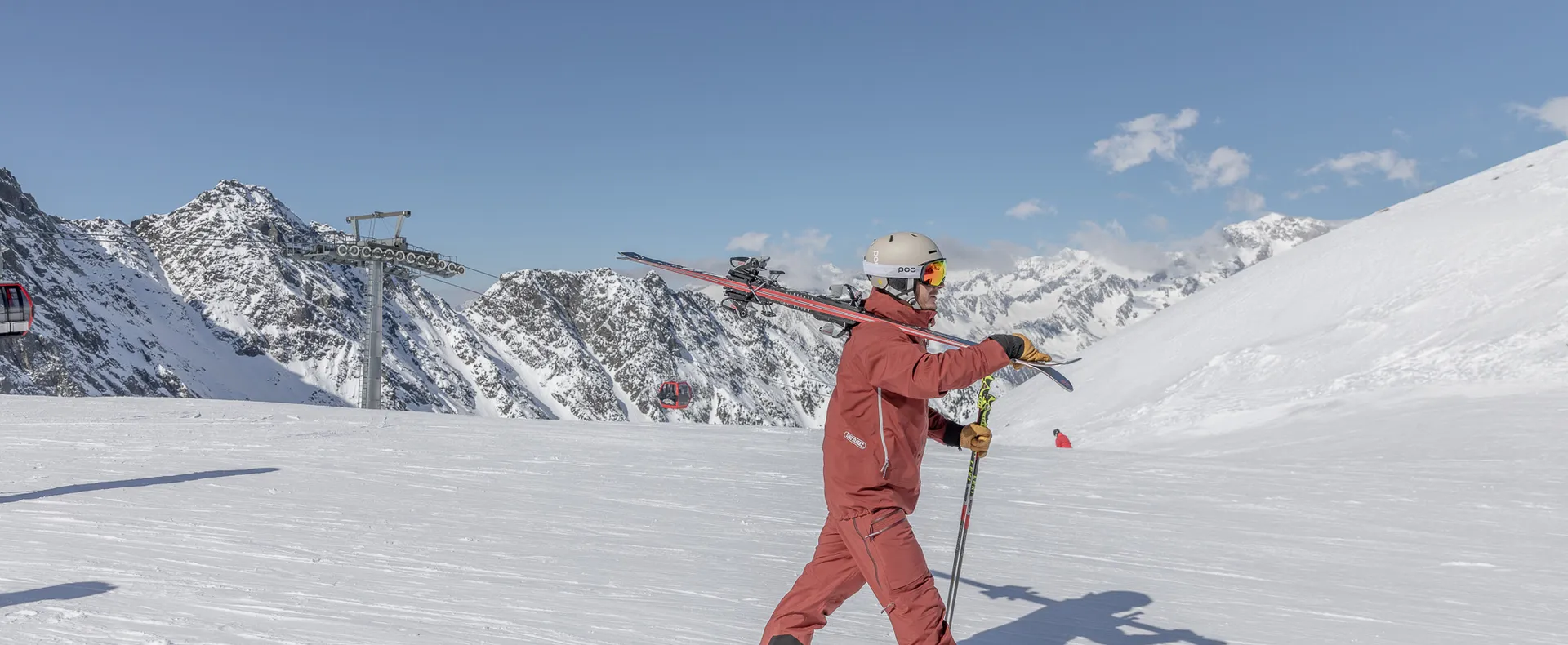 Skifahrer mit Ski über der Schulter auf sonniger Piste am Speikboden mit Blick auf Zillertaler Alpen