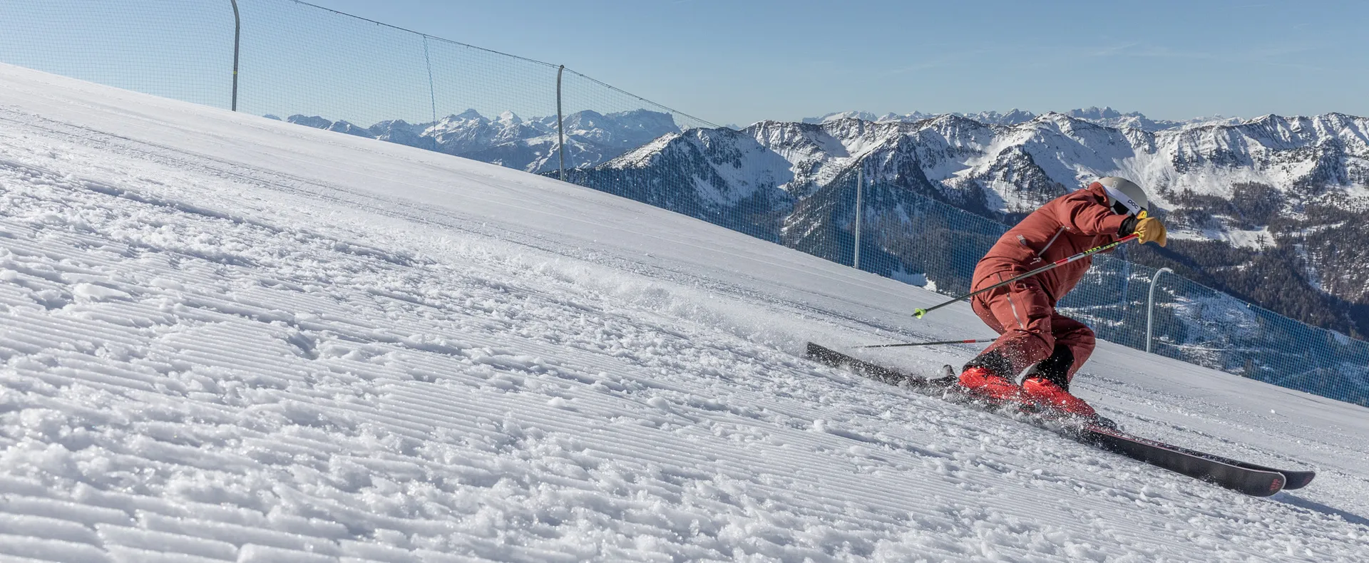 Skifahrer im roten Anzug beim Carving auf perfekt präparierter Piste am Klausberg