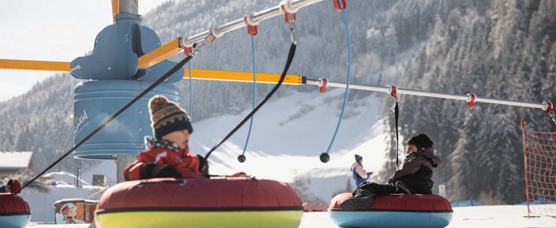 Children on colorful snow tubes on the tubing carousel in the kids' area in Ahrntal