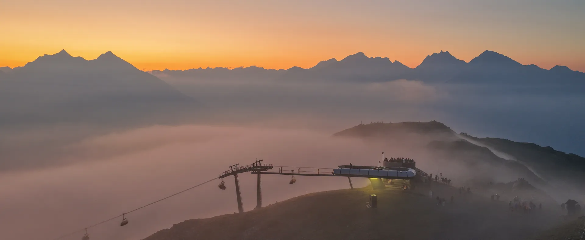 Gondeln der Kabinenbahn am Klausberg bei Sonnenuntergang mit Nebelmeer und Berggipfeln