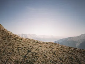 Zwei Wanderer auf sonnigem Höhenweg am Speikboden mit Alpenpanorama