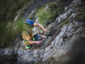 Kletterer greift Stahlseil am Klettersteig Speikboden — Sommerabenteuer Ahrntal