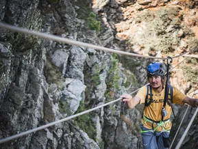 Kletterer am Seilsteg des Klettersteigs Speikboden hält sich an Stahlseilen fest