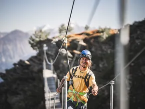 Junger Kletterer auf Hängebrücke am Klettersteig Klausberg mit Blick auf die Tauern