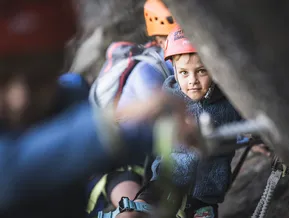 Kind mit Kletterhelm schaut nach oben am Klettersteig Speikboden
