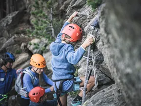 Kind klettert am Klettersteig Speikboden mit Bergführerin und Familie