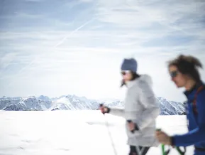 Zwei Schneeschuhwandererinnen mit Blick auf das weite Panorama der Zillertaler Alpen im Ahrntal