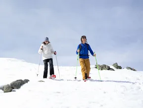 Zwei Schneeschuhwanderer beim Aufstieg über verschneiten Felsenhang am Klausberg im Ahrntal