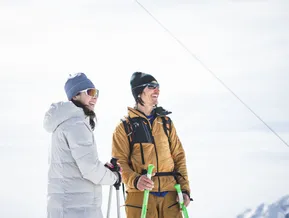 Lachendes Paar mit Schneeschuh-Stöcken und Winterausrüstung am Berggipfel im Ahrntal