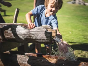 Child happily plays at the water playground at Klausberg in Ahrntal