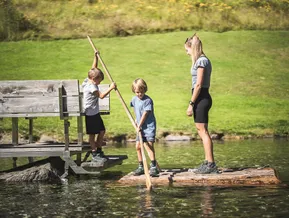 Children on wooden raft at the mountain lake at Klausberg Ahrntal