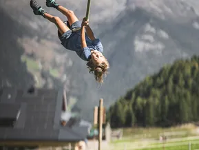 Laughing child hanging upside down on zip line at Klausberg mountain adventure park