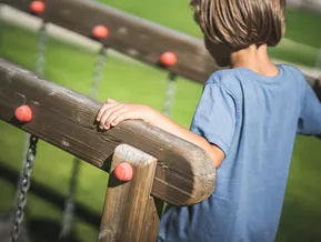 Child plays on wooden railing of the adventure playground in Ahrntal