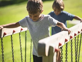 Two boys balance on a chain bridge at the Klausberg adventure park