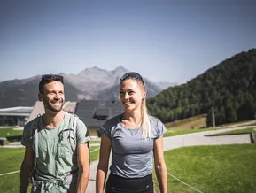 Smiling hiking couple in summer at Klausberg with mountain panorama in the background