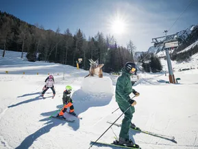 Skifahrer an der Triceratops-Figur der Dino Sun Line am Klausberg – Dinosaurier-Themenbereich auf der Skipiste