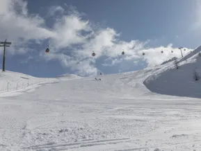 Breite präparierte Skipiste am Klausberg im Ahrntal mit roter Gondelbahn und blauem Winterhimmel