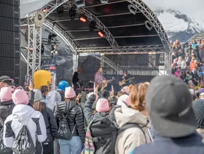 Sänger mit Gitarre auf der Bühne und tanzendes Publikum beim Bergkonzert im Skigebiet Klausberg