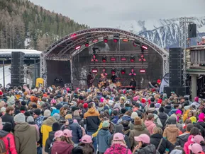 Open-Air-Konzert am Berg mit Band auf professioneller Bühne vor schneebedeckten Gipfeln
