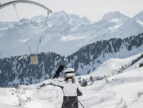 Skifahrerin am Foto-Spot mit Kuhglocke vor Alpenpanorama im Skigebiet Klausberg