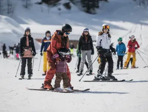 Skistunde für Kinder am Klausberg – Snowboarderin zeigt kleinem Kind die ersten Schritte auf Skiern