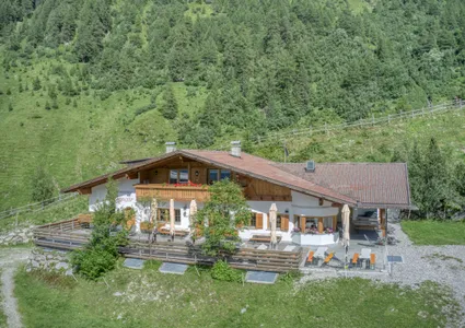 Berggasthaus mit Sonnenterrasse und Liegestühlen auf Almwiese im Sommer