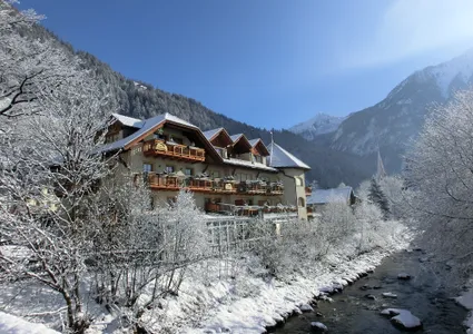 Traditionelles Hotel am Gebirgsbach im verschneiten Ahrntal Südtirol