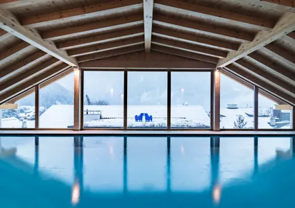 Hallenbad mit Holzdach und Panoramafenster im Wellnesshotel Ahrntal