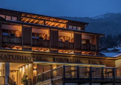 Naturhotel Moosmair im winterlichen Ahrntal bei Dämmerung mit beleuchteter Holzfassade und Schnee
