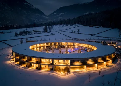 Beleuchtetes rundes Hotel im verschneiten Ahrntal bei Nacht mit Bergpanorama im Hintergrund