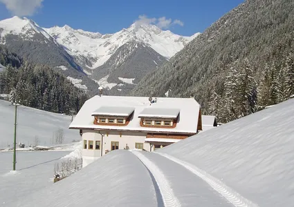 Verschneites Südtiroler Bauernhaus im Ahrntal mit Blick auf die Zillertaler Alpen